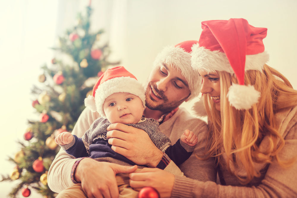 Young couple with baby wearing Christmas hats